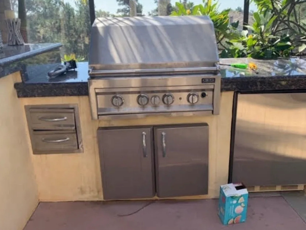 Outdoor kitchen with built-in BBQ and storage drawers.