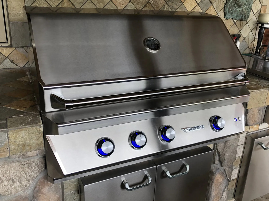 Stainless steel BBQ grill with blue control knobs.