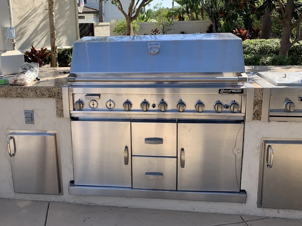 Stainless steel BBQ grill in outdoor kitchen setup.