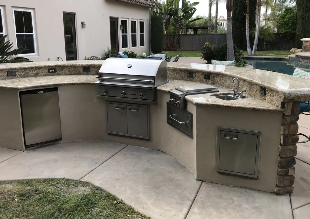 Outdoor grill station with sink and storage compartments.