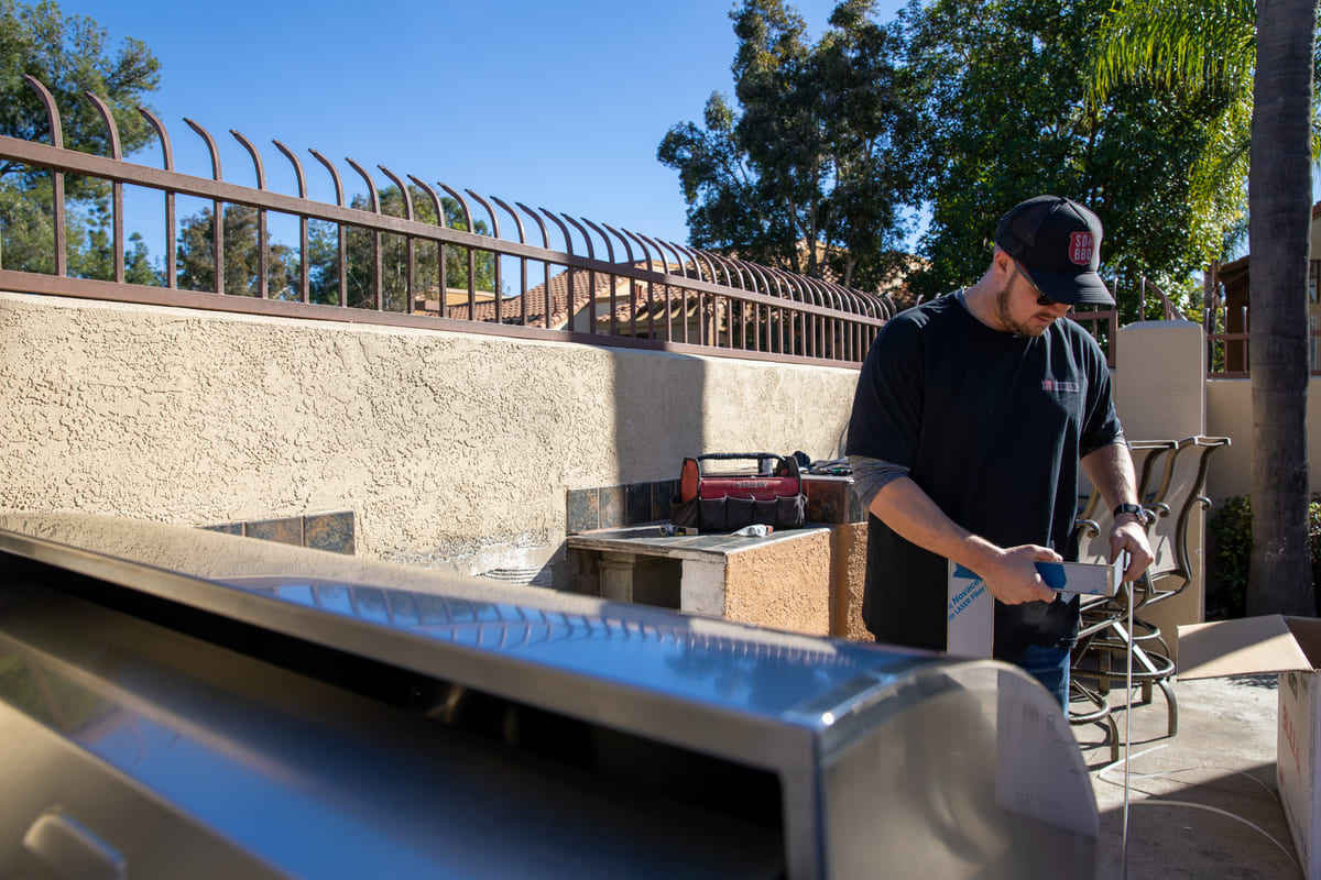 Technician installing outdoor grill in backyard patio.