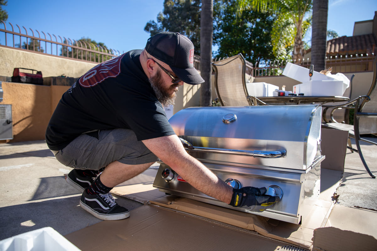 Man installing stainless steel grill outdoors.