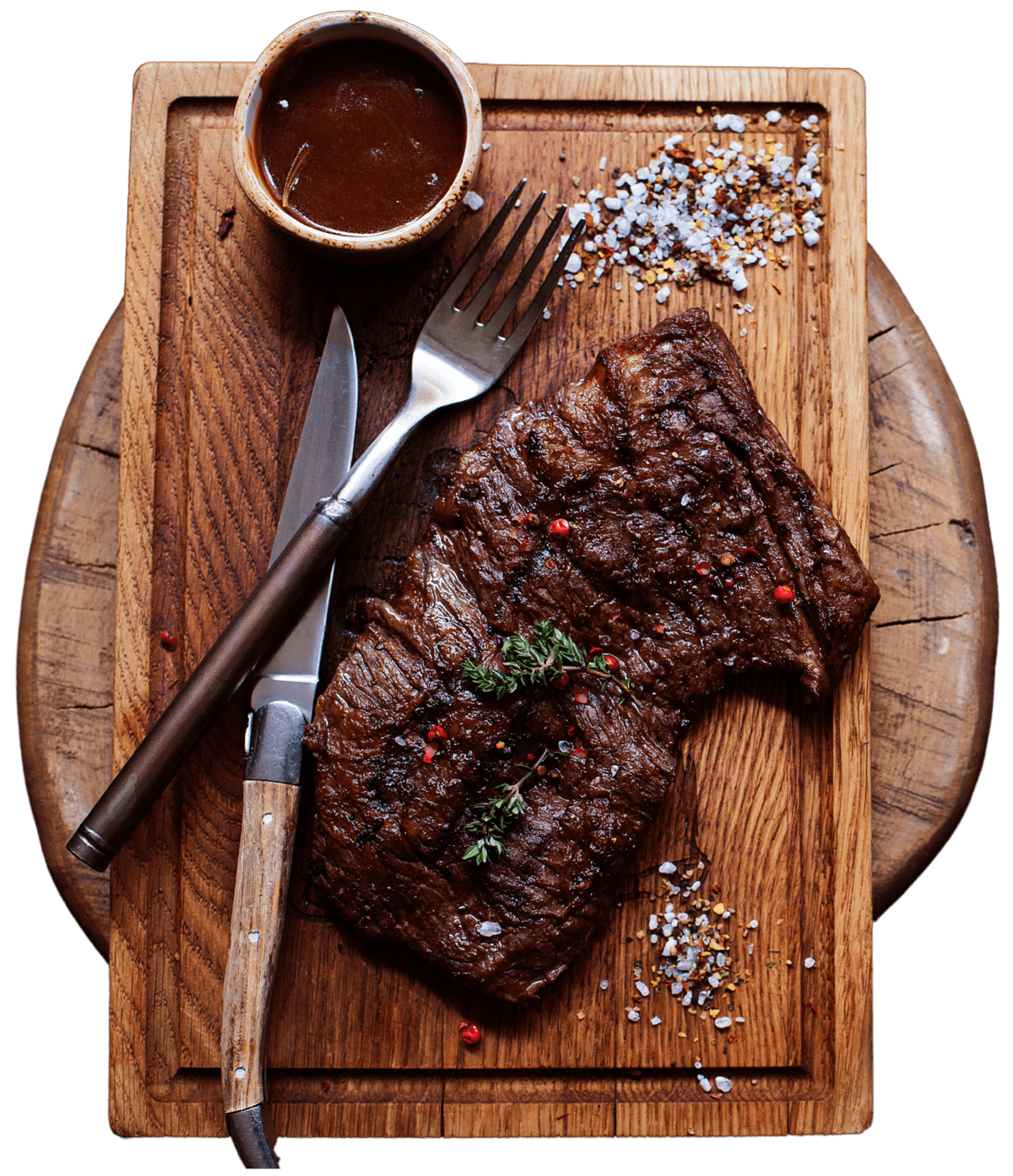 Grilled steak on wooden board with sauce and spices.