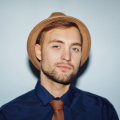 Stylish man with beard wearing blue shirt and hat.