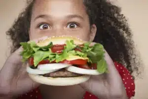 Child biting into a large gourmet hamburger