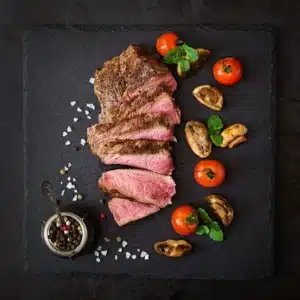 Sliced medium-rare steak with tomatoes and mushrooms