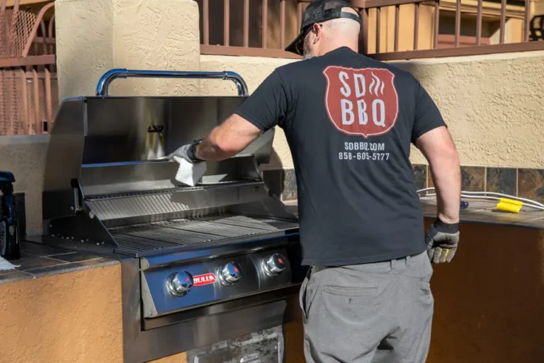 Man in SDBBQ shirt professionally cleaning a stainless steel BBQ