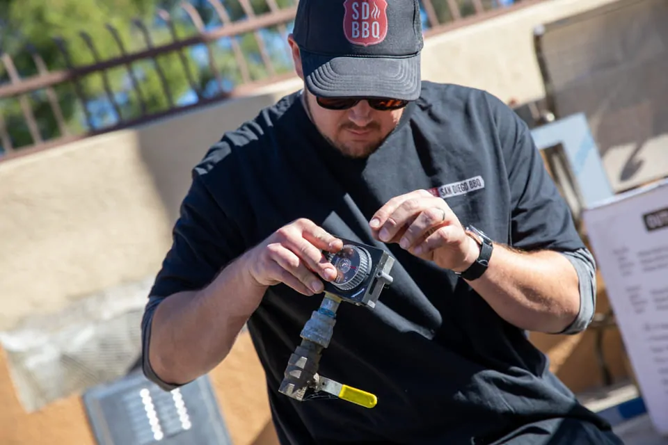 BBQ technician repairing grill burner outdoors