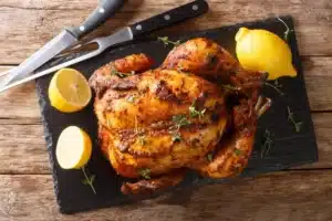 Roasted whole chicken with herbs on a slate board