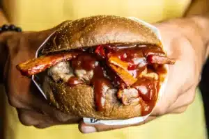 Hand holding a juicy BBQ pulled pork sandwich