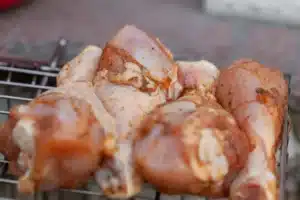 Raw seasoned chicken drumsticks on a grill