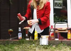 Woman dressing a hamburger at an outdoor picnic