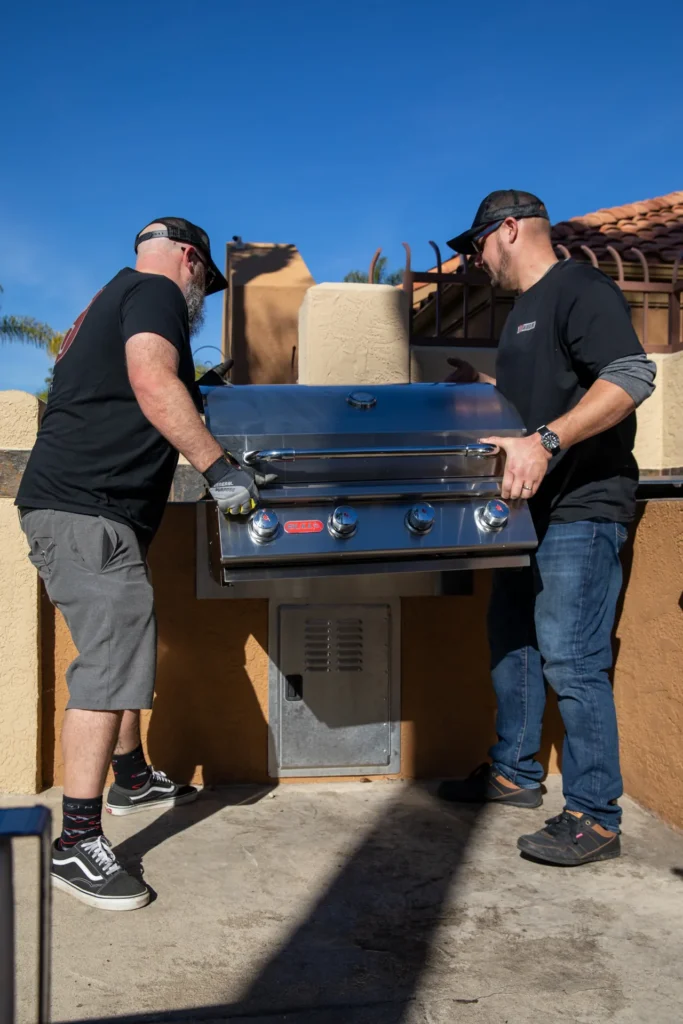 Two SDBBQ technicians carrying a new grill to an island