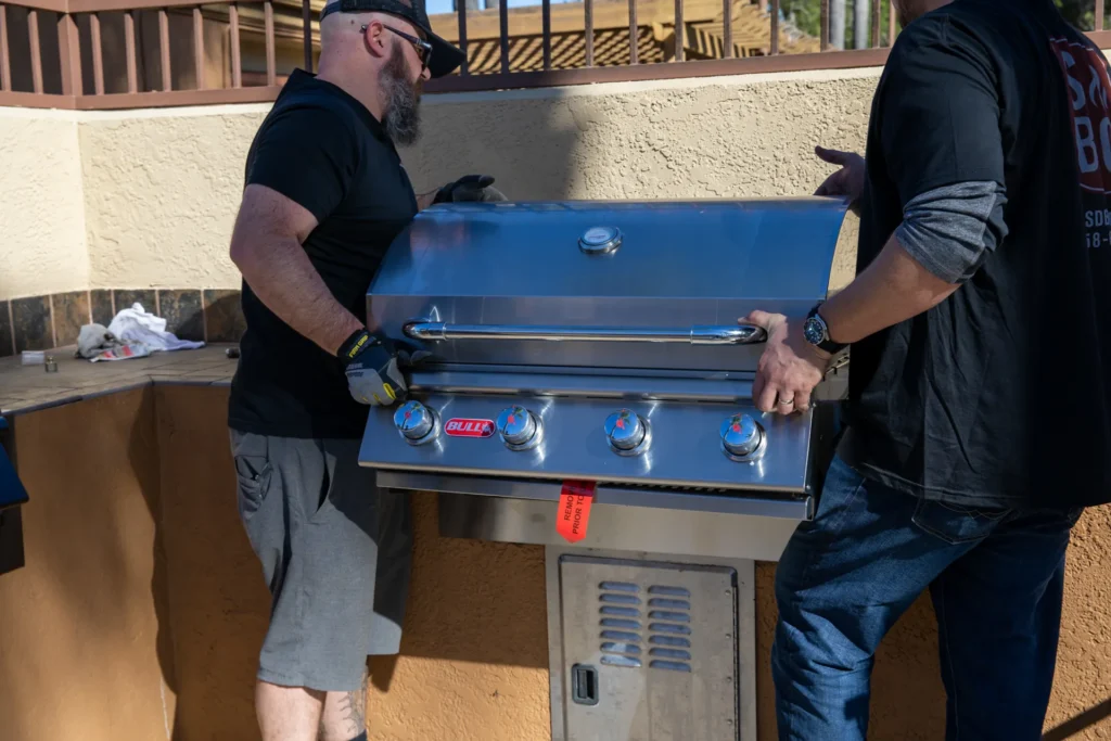 Two SDBBQ technicians setting a new built-in grill into an island