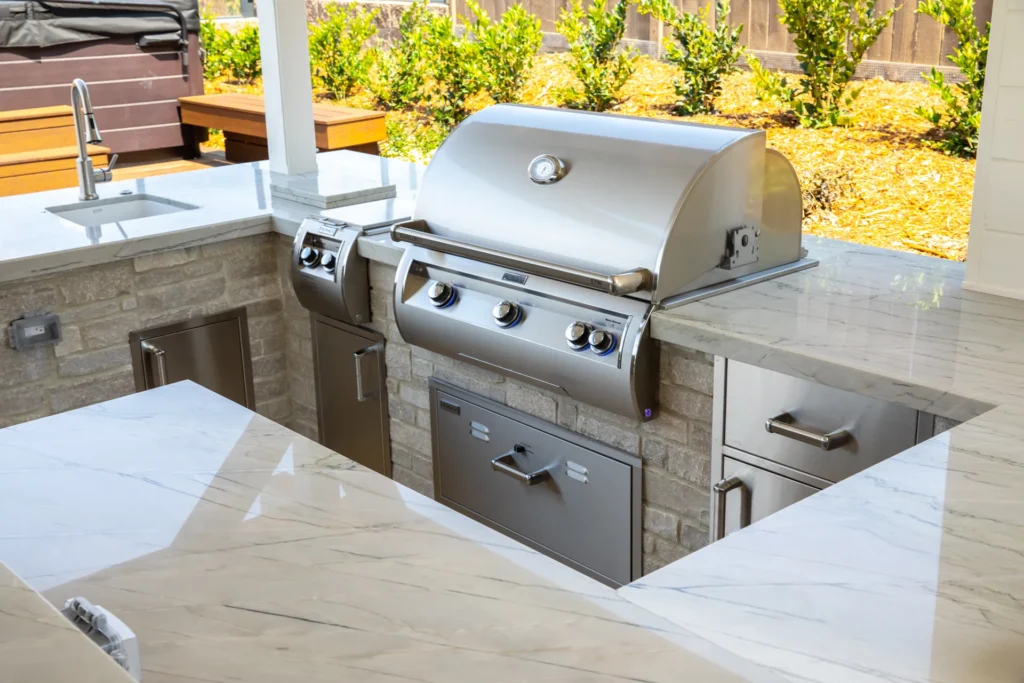 A finished outdoor kitchen with a built-in grill, side burner and stone counters