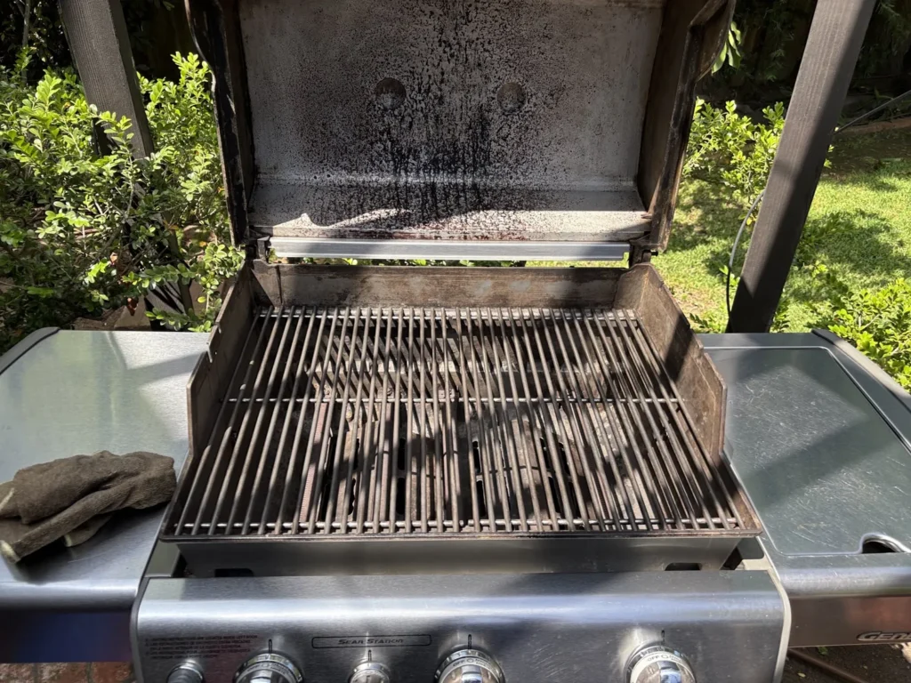 A Weber Genesis gas grill after cleaning, with scrubbed grates and a degreased hood