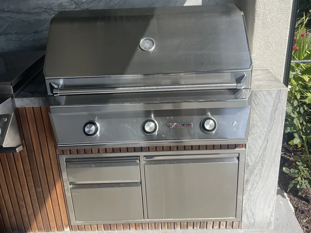 Polished 36-inch Twin Eagles built-in grill with stainless drawers in a stone and wood outdoor kitchen