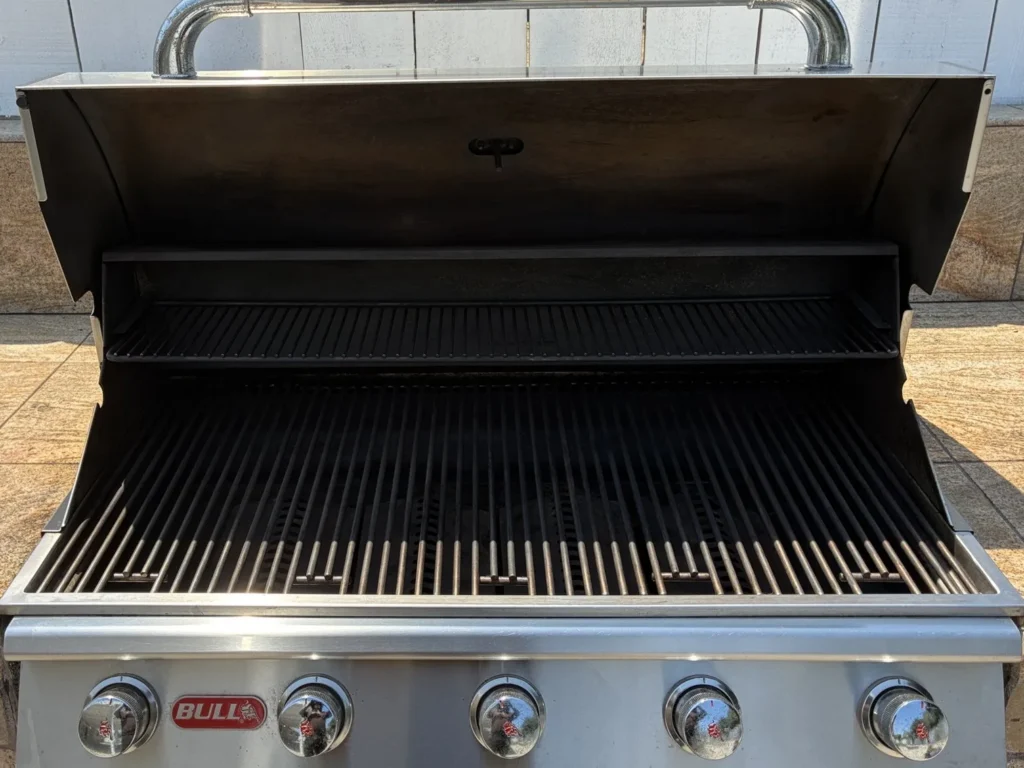 Clean Bull 38-inch five-burner built-in gas grill with the hood open in a tiled island