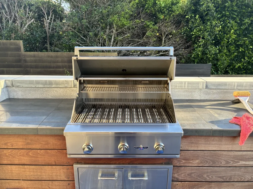 A clean 32-inch Delta Heat built-in grill, lid open, in a tiled wood island