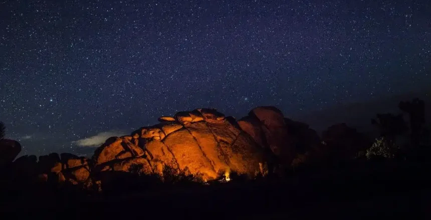Starry night over illuminated rock formation