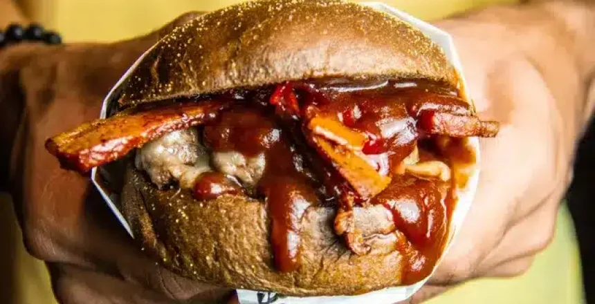 Hand holding a juicy BBQ pulled pork sandwich